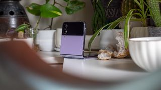 The Galaxy Z Flip 4 Bora Purple in flex mode on a table next to a shiny geode