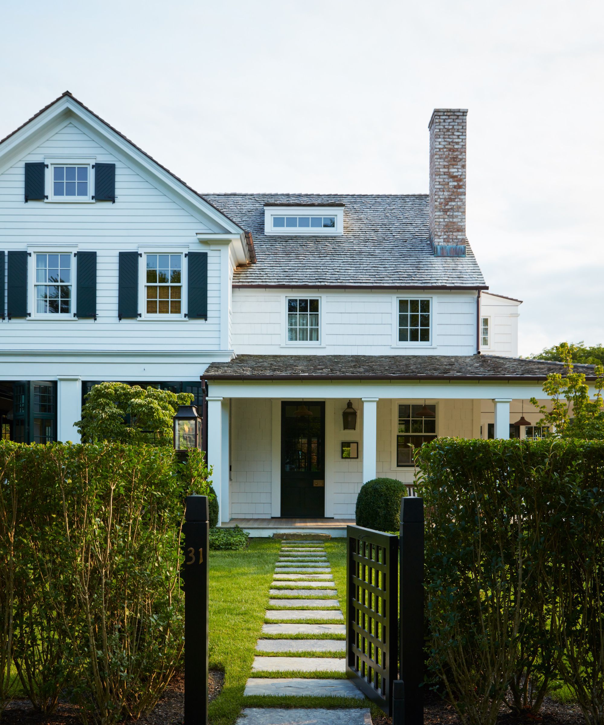 Bryan Graybill's white wood-clad house with dark shutters, a veranda and a garden gate and path leading up to it