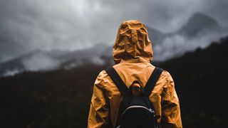 Hiker wearing waterproof jacket looking out at incoming storm