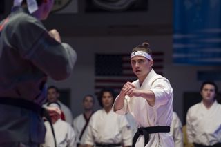 a karate star in a white uniform gets ready to fight in cobra kai season 6 part 3