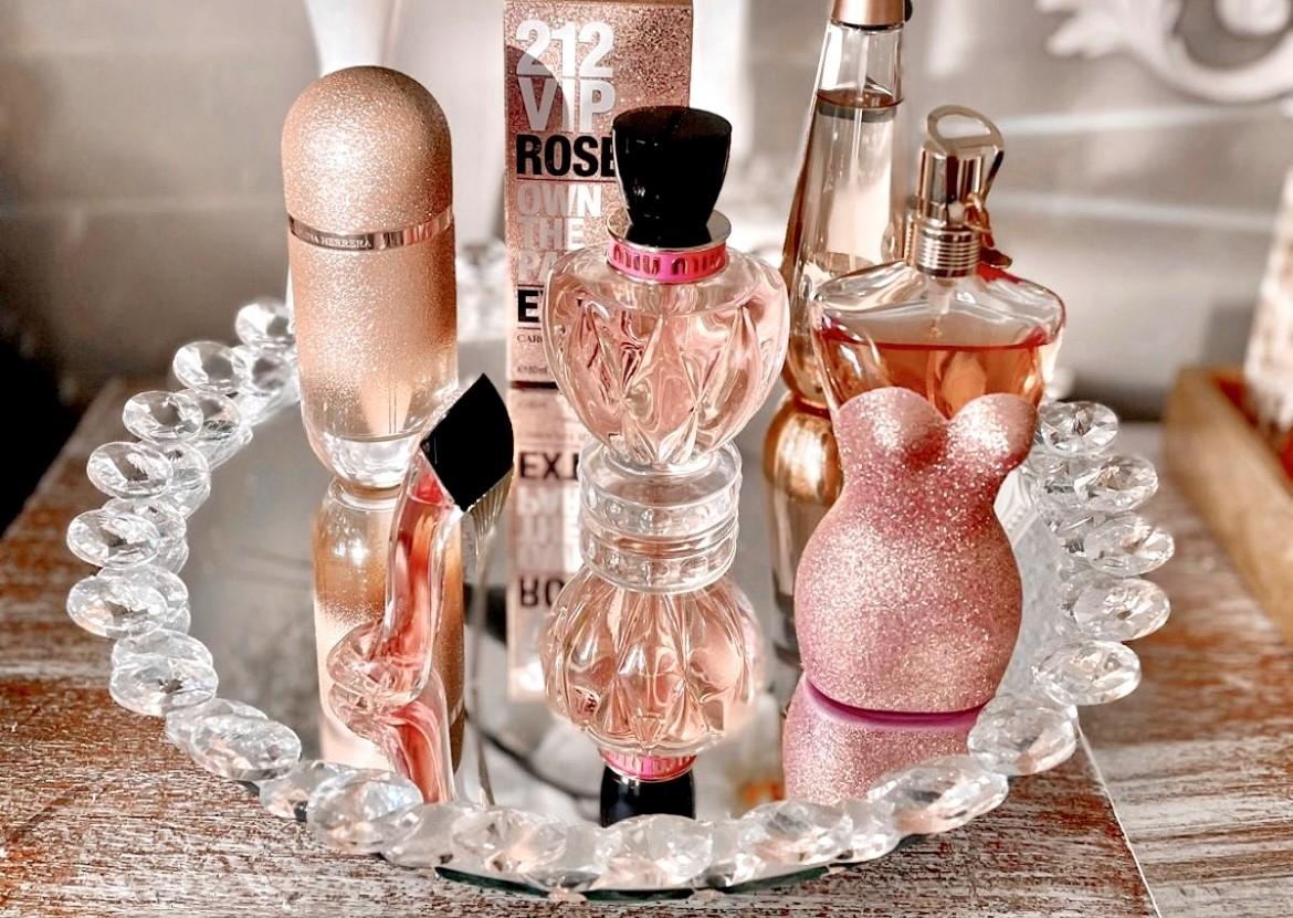  A chic vanity display with pink and gold perfume bottles on a crystal tray. 