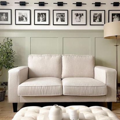 living room with white sofa and pouffe with green wall panelling