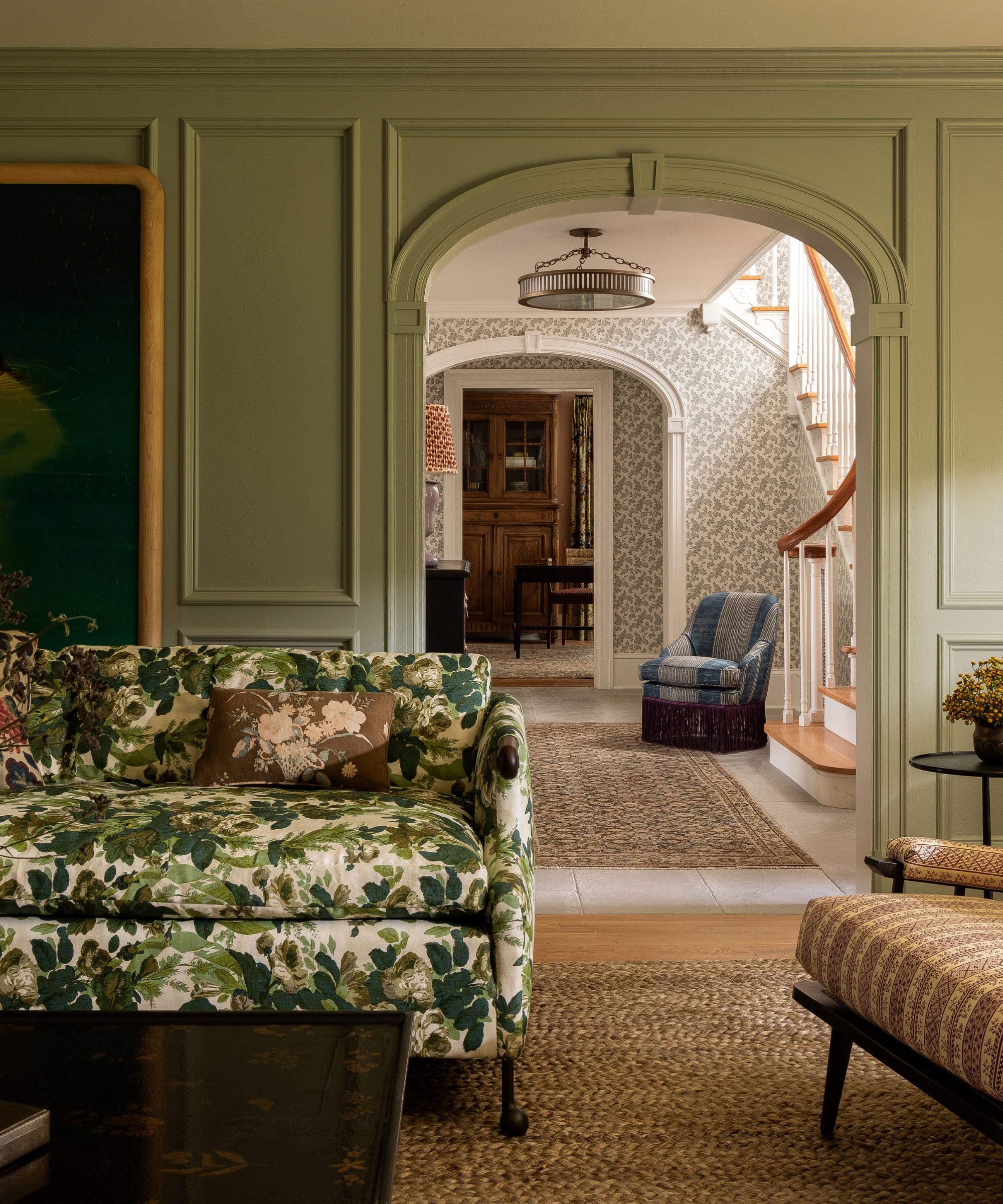 A green living room designed by Heidi Caillier with a patterned couch and arched doorway
