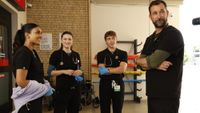 Javadi, Santos, Whitaker, and Robby standing around in the ambulance bay on The Pitt.