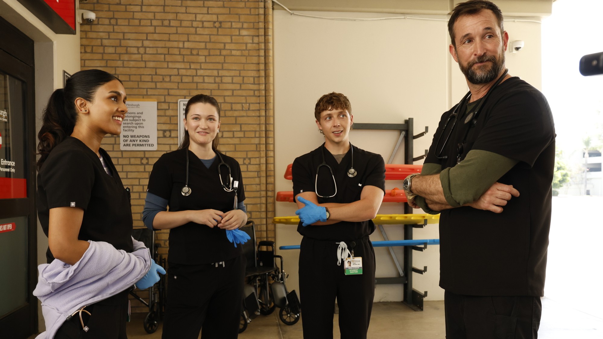 Javadi, Santos, Whitaker, and Robby standing around in the ambulance bay on The Pitt.