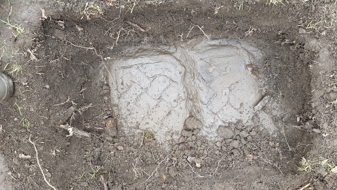 A Govan Stone emerges from the dirt.
