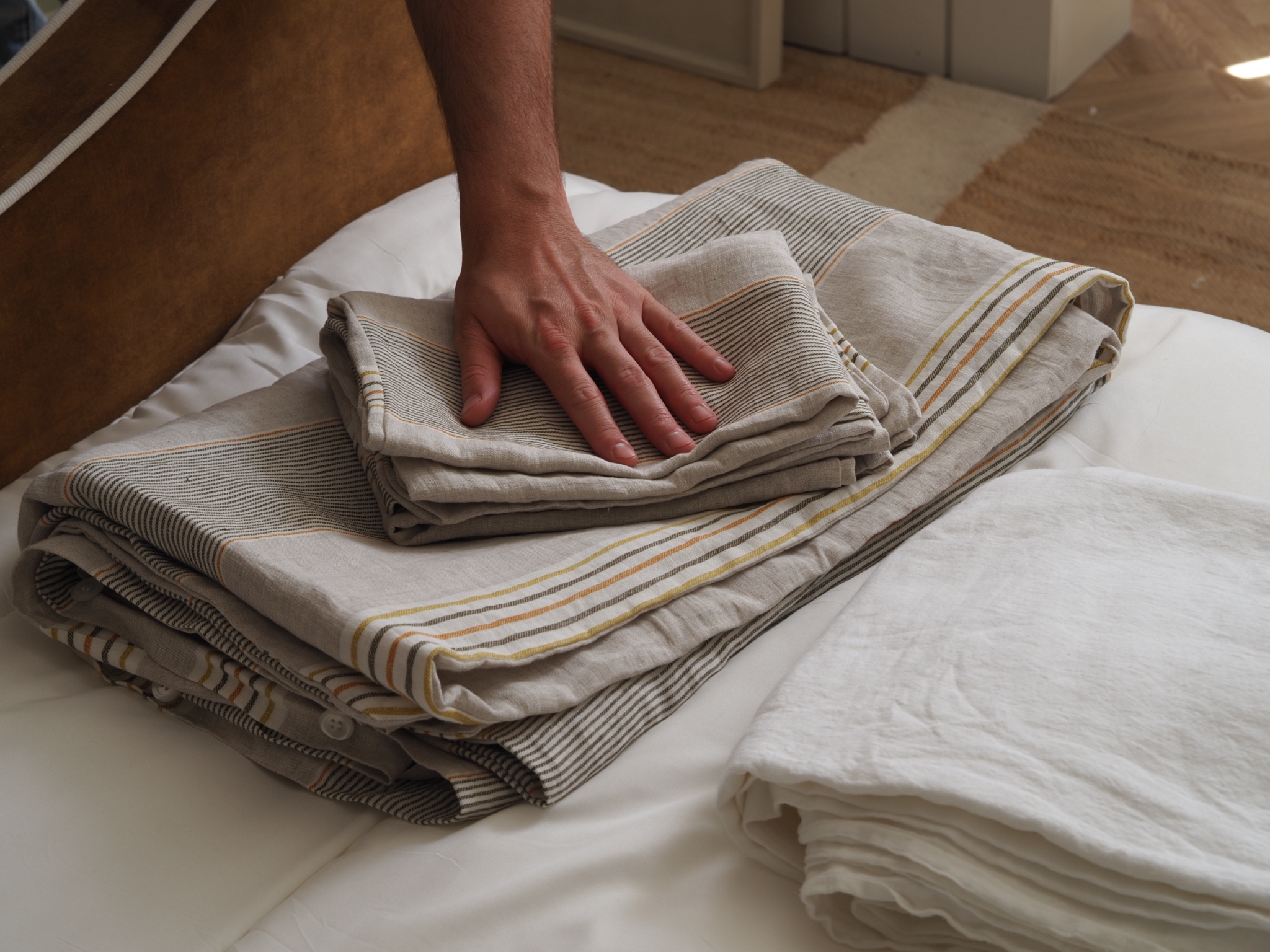 striped linen bedding being touched by a hand