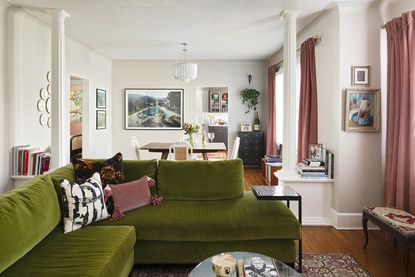 open plan living room dining room combo with green sofa and pink curtains