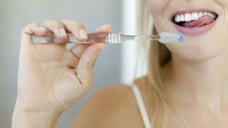 Should you brush your tongue: image shows woman cleaning teeth