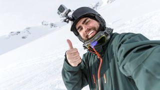 Man wearing GoPro camera on helmet giving a thumbs-up