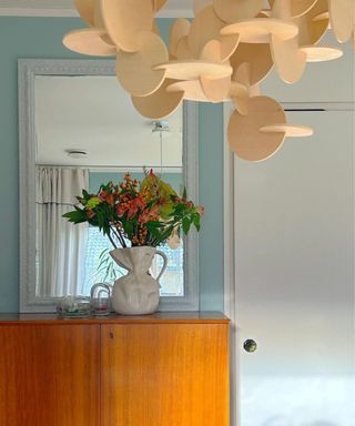 A blue hallway with a white door and console table with a vase of flowers on it