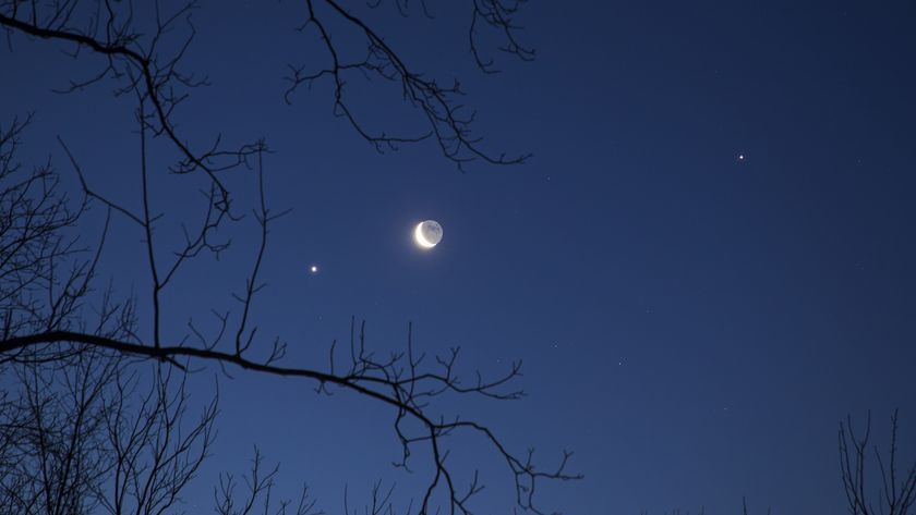 A photo of a crescent moon with brightly shining planets and stars