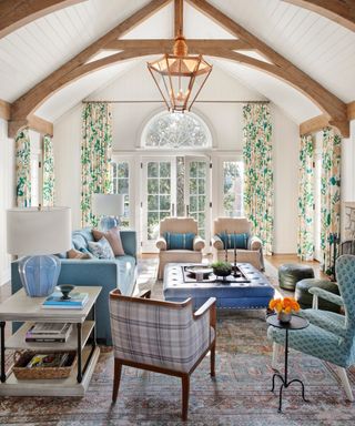 living room with vaulted ceiling, green floral curtains, blue sofa and patterned armchairs