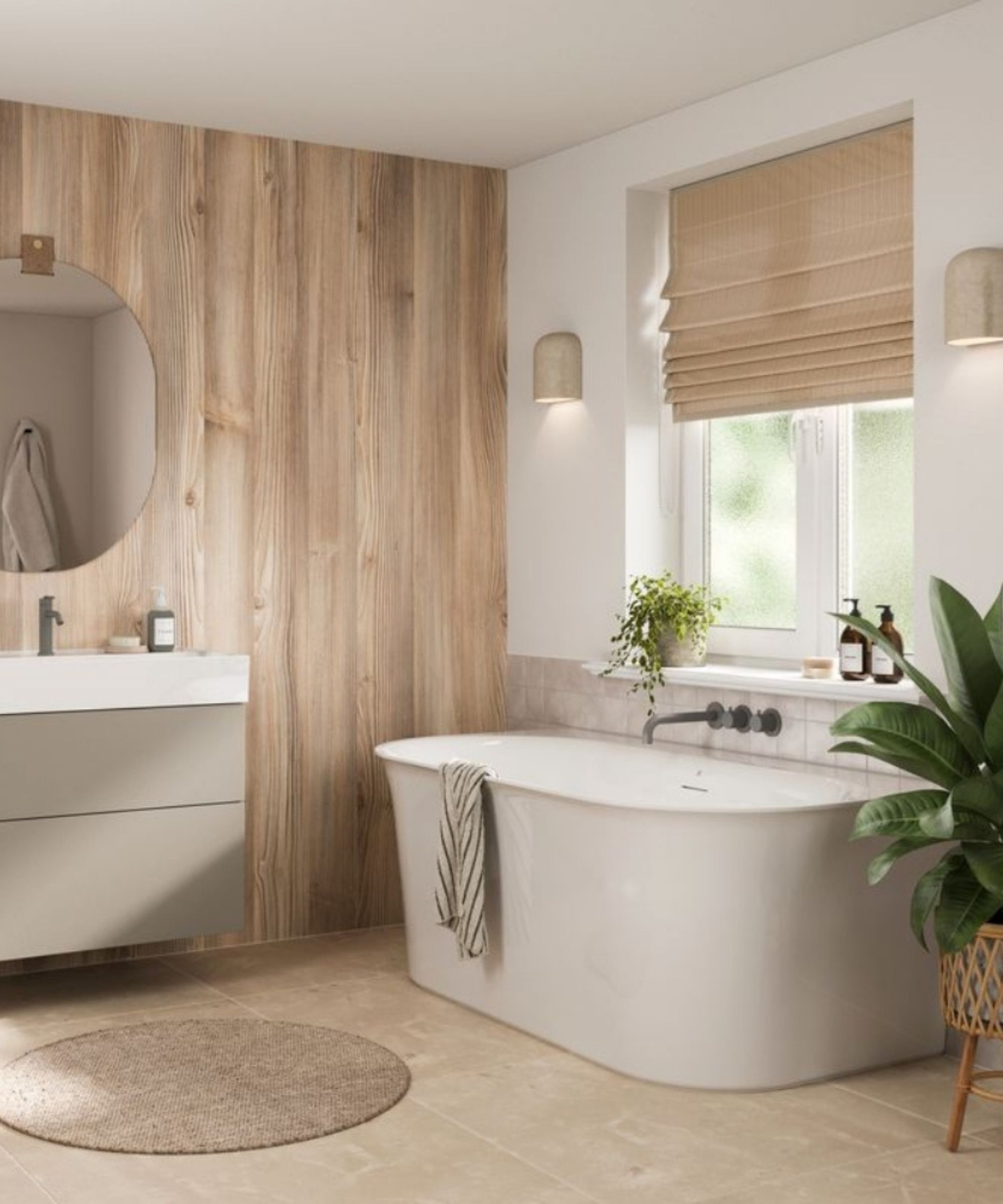 A calm, natural bathroom with a tall light pine wood-effect feature wall behind a white freestanding rectangular bath with matte grey wall-mounted taps. A sage green floating vanity with round mirror, woven roman blind, jute bath mat and large tropical plants complete the warm Scandinavian-inspired scheme.