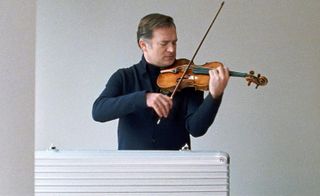 Man playing violin, with Rimowa violin case open in front