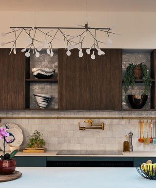 brown and blue kitchen with pearlescent tile backsplash, white countertops, wooden upper wall cabients,