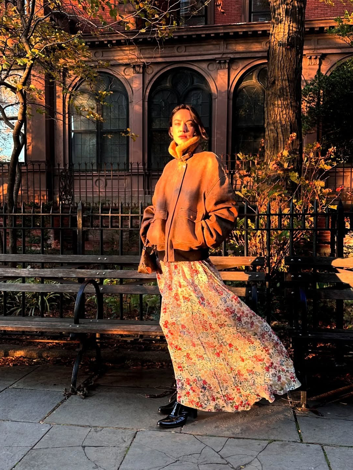 Alexa Chung wearing a shearling jacket with a funnel neck from Khaite with a floral maxi dress and tall boots.