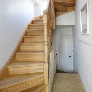 A white hallway with wooden staircase