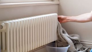 Hand with towel next to radiator with bowl under it