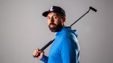 Rick Shiels wearing a blue hoody posing for a photo with his putter of his shoulder