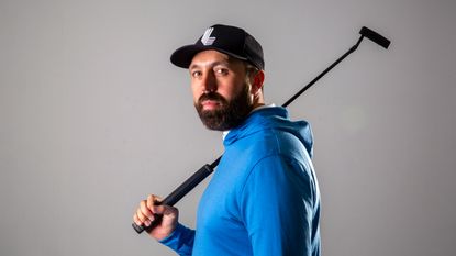 Rick Shiels wearing a blue hoody posing for a photo with his putter of his shoulder