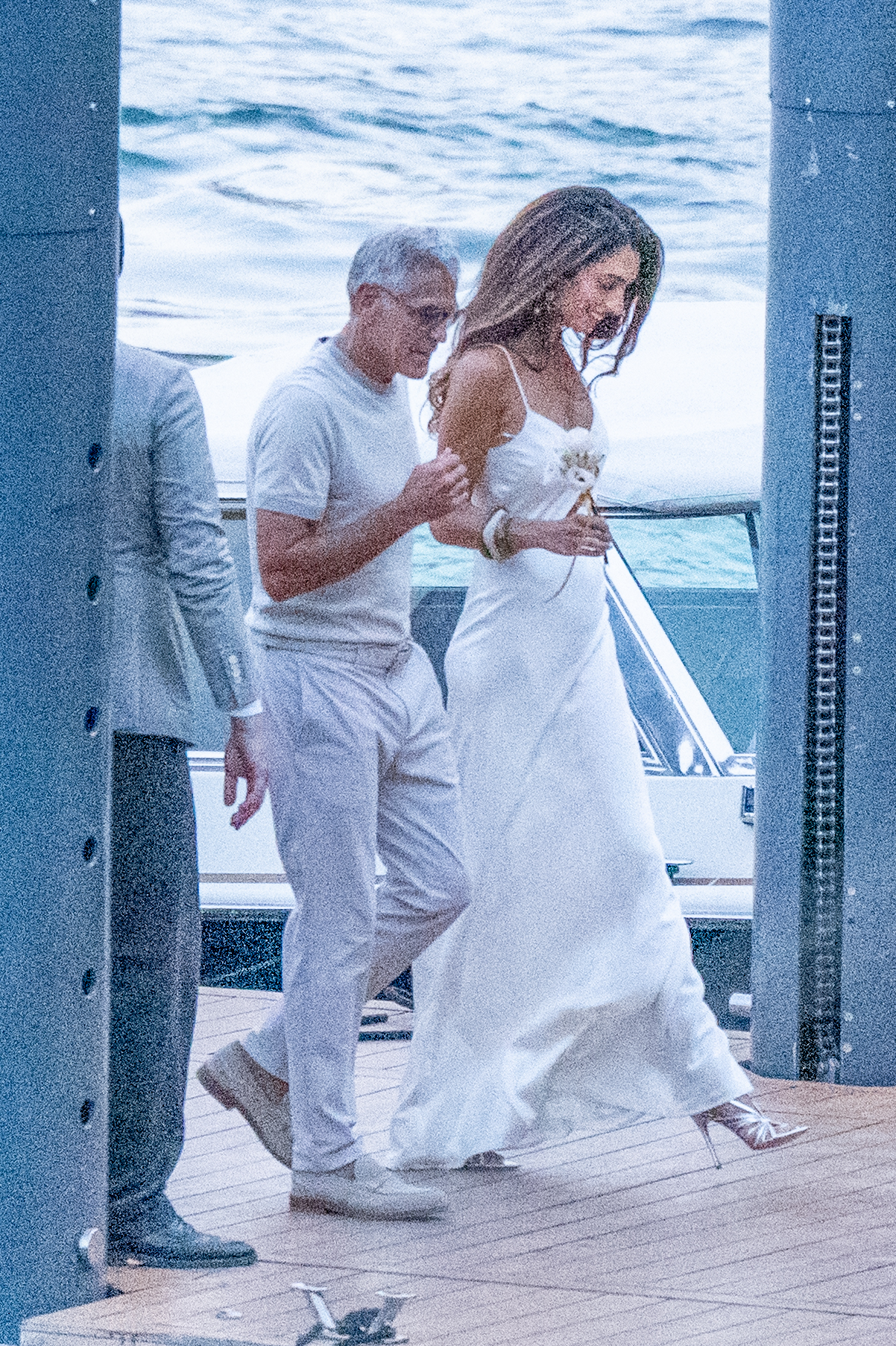 An image of Amal Clooney in Lake Como wearing a white slip dress and silver heels.