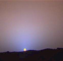 a close up view of a sunset on mars, the sky around the sun is tinted blue.