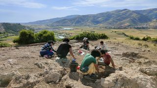 a group of people excavate a site with mountains behind them