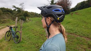 female mountain biker in the countryside wearing a black Giro Montara helmet
