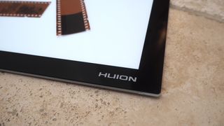 Close up of the brand name on a Huion L4S light pad on a beige stone slab surface