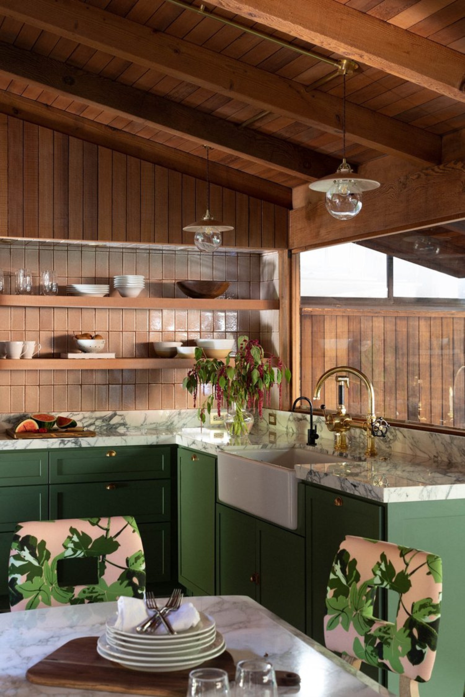 a green and timber kitchen with pink and green dining chairs