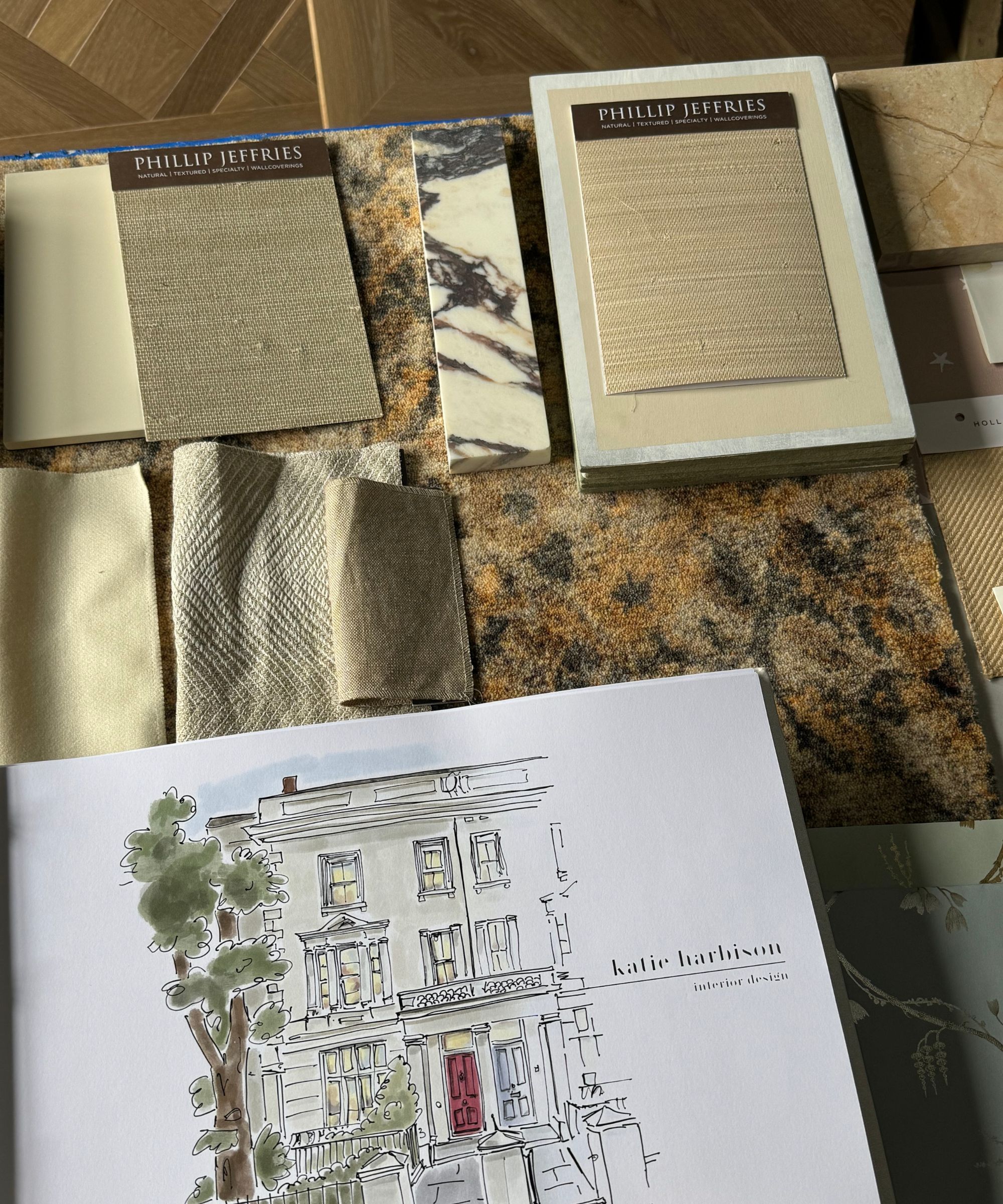 Painted sketch of house exterior on white paper, surrounded by fabric and material samples on table
