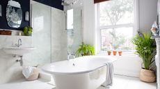 a white bathroom with a role top bath and marble walls and floors 