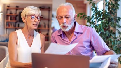 An older couple look unsure as they look at paperwork together.