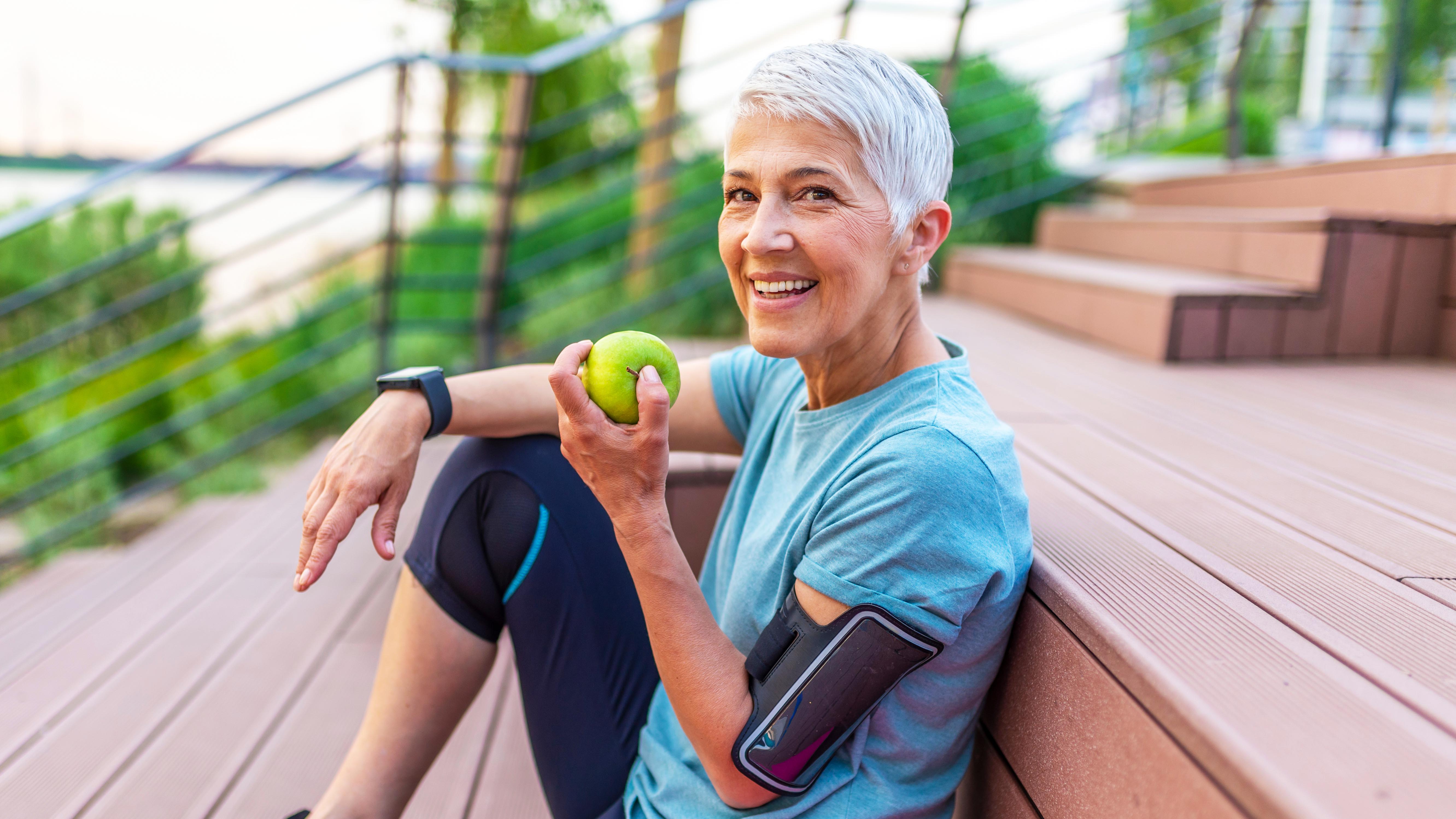 a senior woman eating an apple after exercise