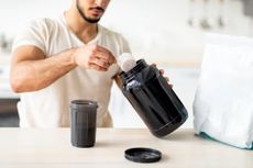 man scooping protein powder into his shaker