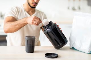 man scooping protein powder into his shaker