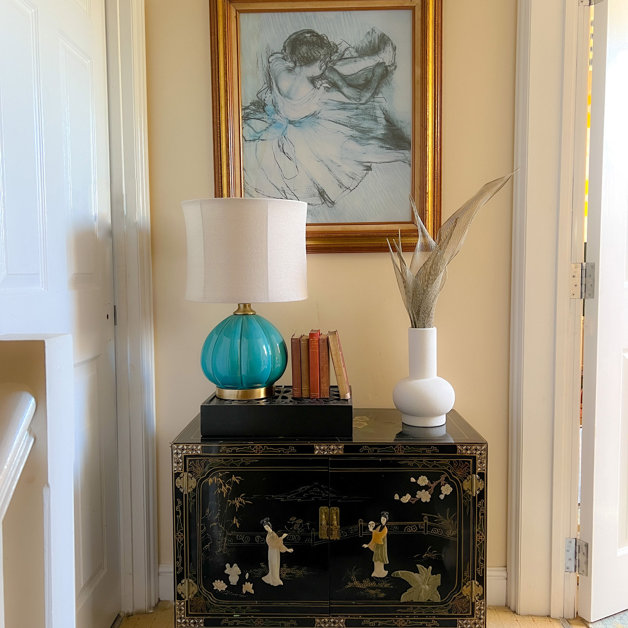 black chest with a blue lamp and white vase on it