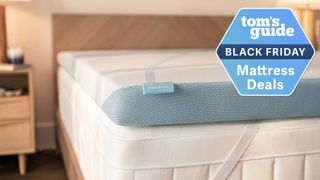 A close up of the Tempur-Pedic Tempur-Adapt mattress topper strapped to the top of a Tempur-Pedic mattress in a bedroom, a Tom's Guide Black Friday mattress deals graphic (right)