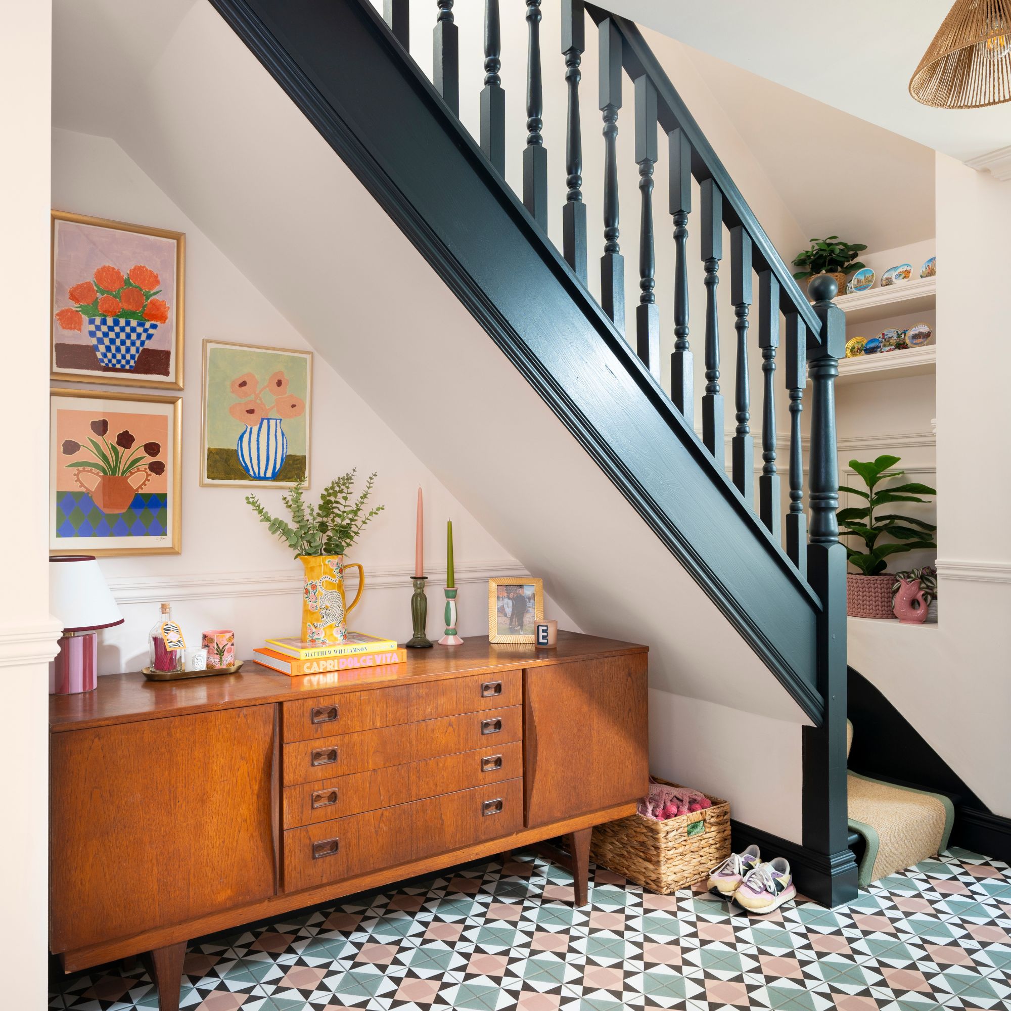 Hallway with colourful tiled floor and a wooden cabinet underneath the stairs