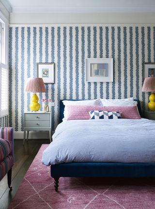 bedroom in Jessica Buckley's home with blue striped wallpaper, yellow lamps and a pink rug