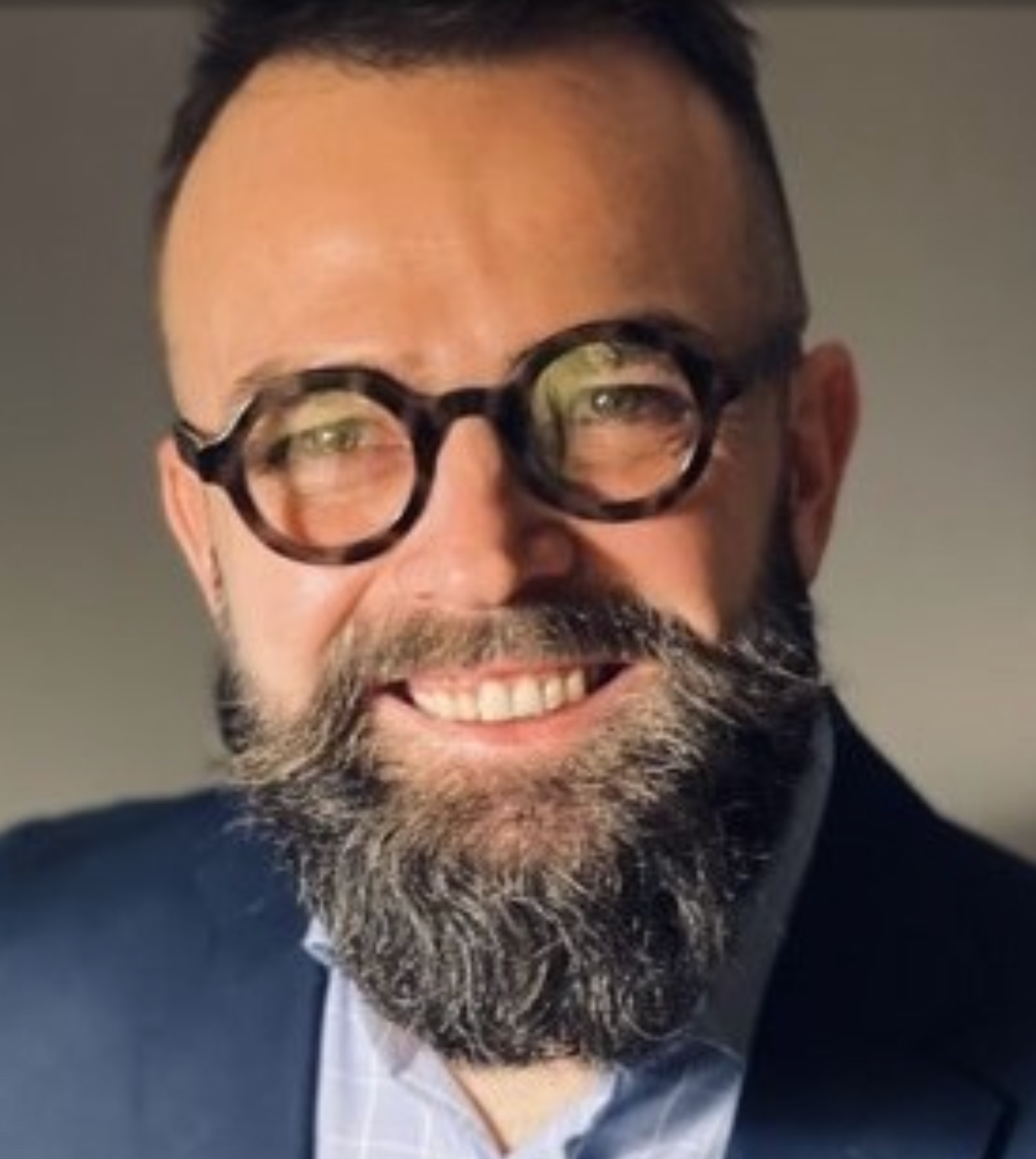 A man with circular glasses and a beard.