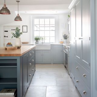pale blue kitchen with darker island and flagstone floors