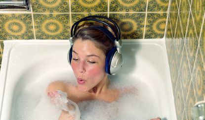 Woman listening to music in the bath using headphones