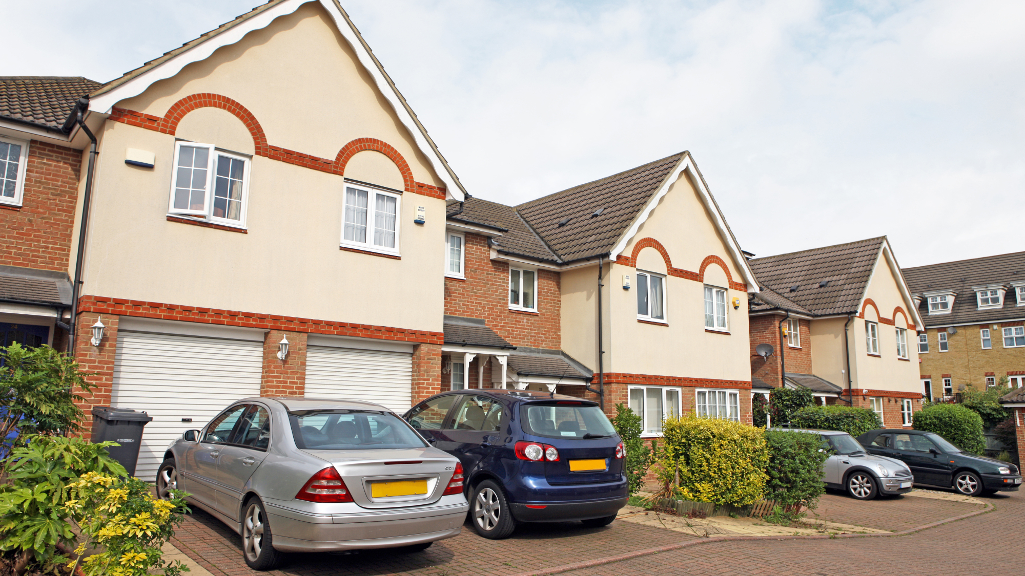 cars parked on driveways of suburban residential street of new build style homes