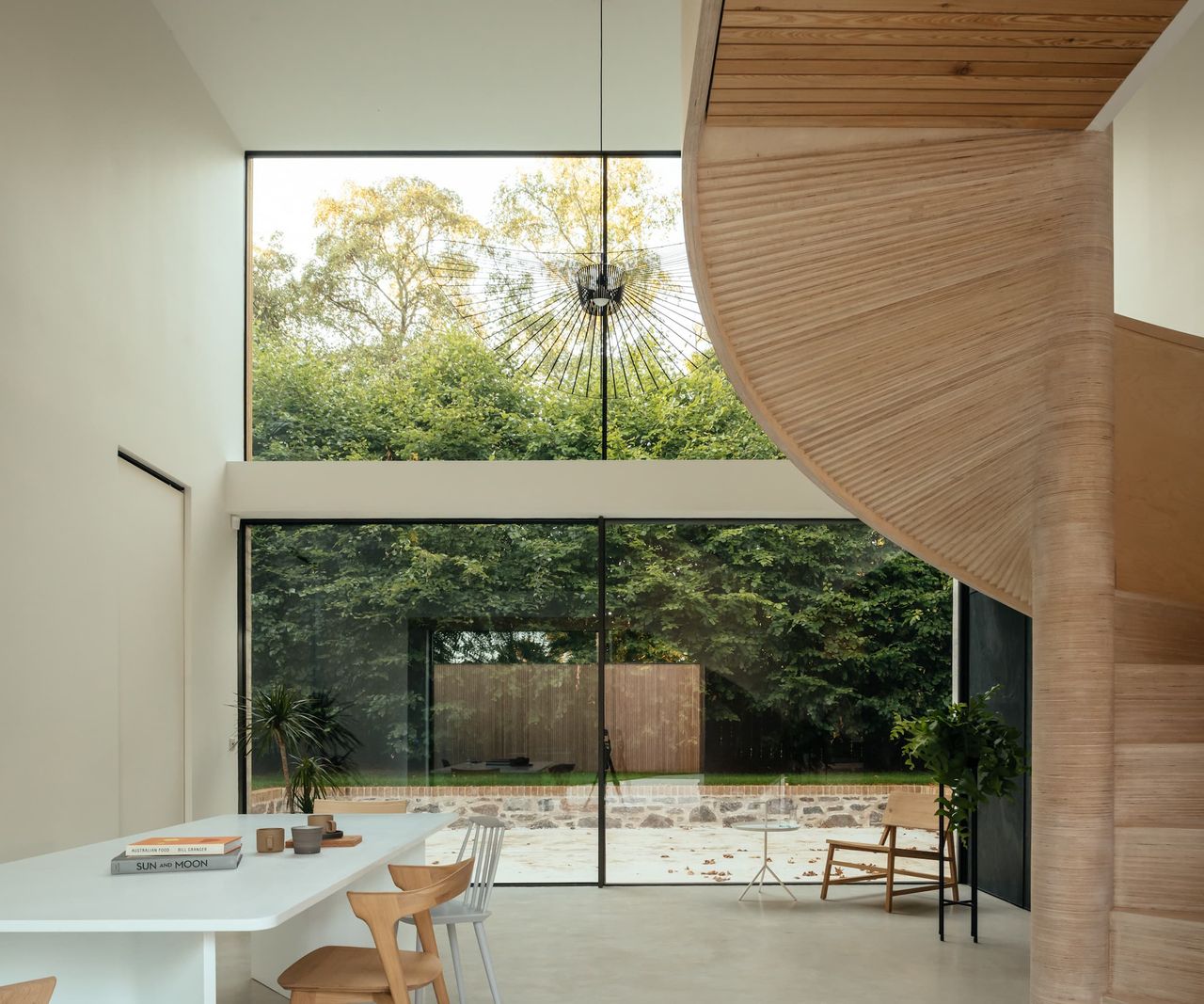 A curved wooden staircase facing a tall picture window