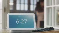A Google Nest Hub showing its digital clock and clear weather.