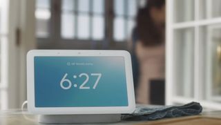 A Google Nest Hub showing its digital clock and clear weather.