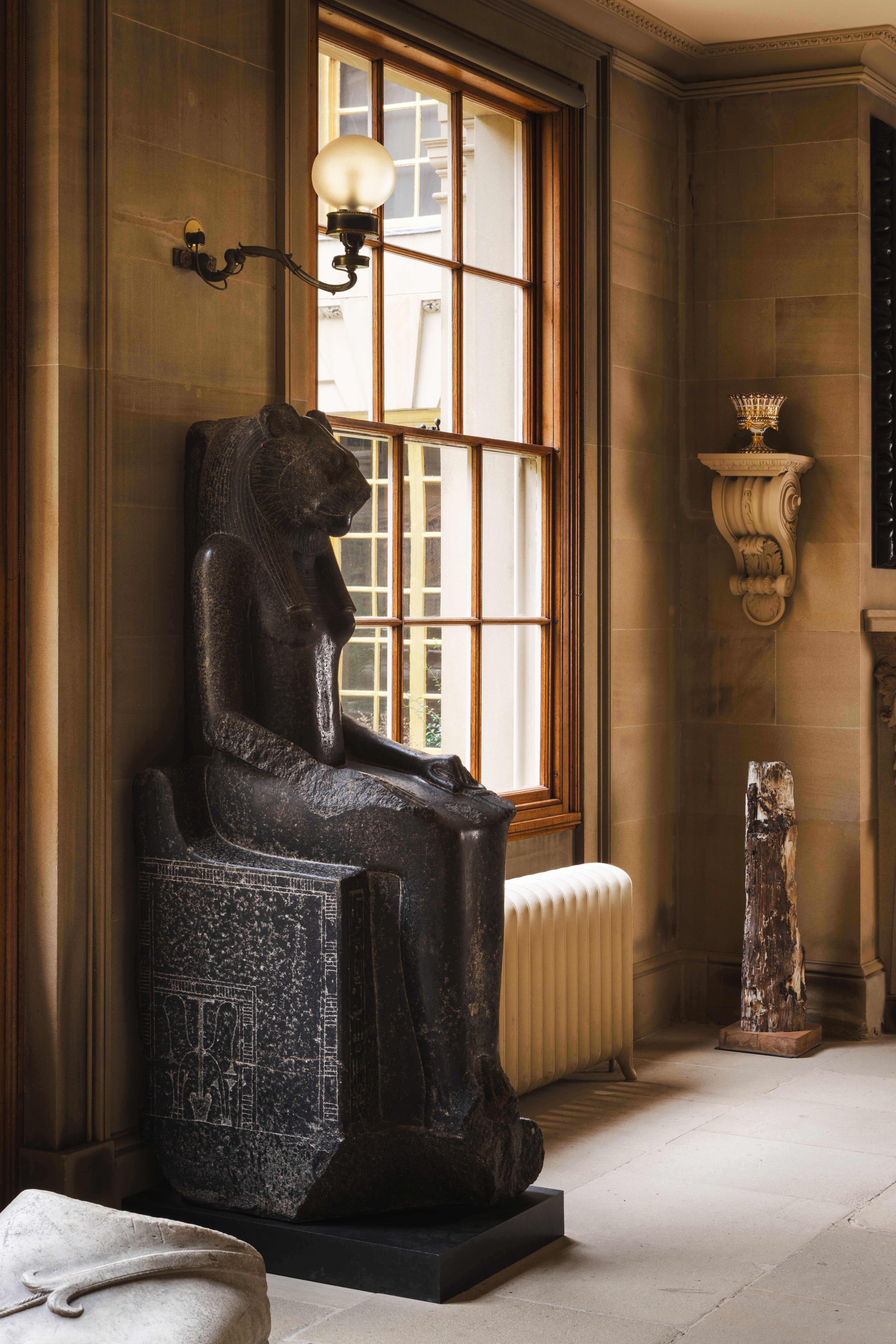 Egyptian statue in a stone room with double height windows