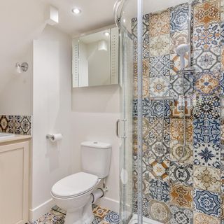 bathroom with printed design tiles and commode